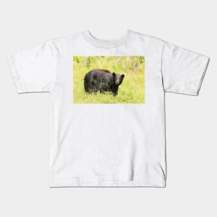 Black bear in a green field Kids T-Shirt